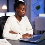 Bookkeeper woman with dark skin looking into laptop computer calculate